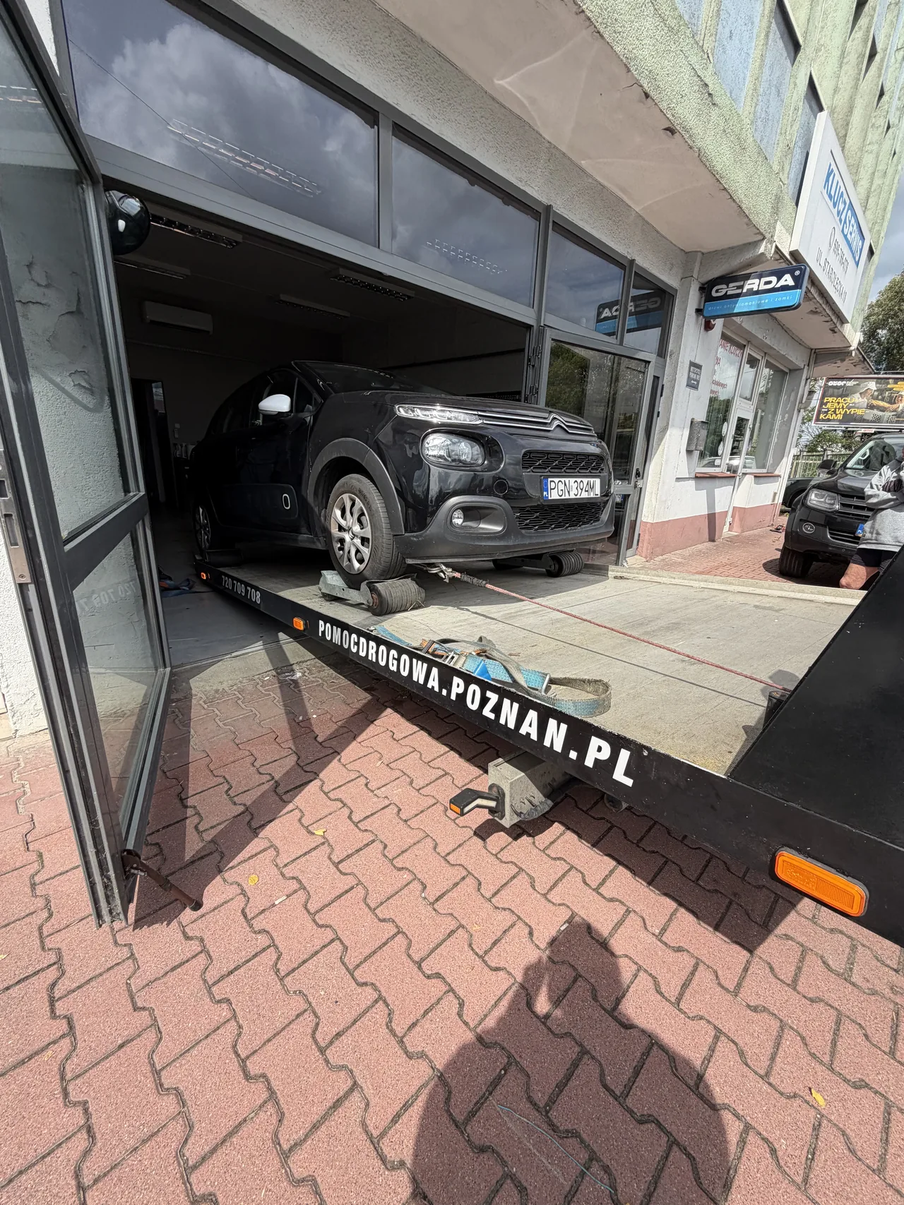 Czarny samochód z zablokowanymi kołami wciągany na platformę