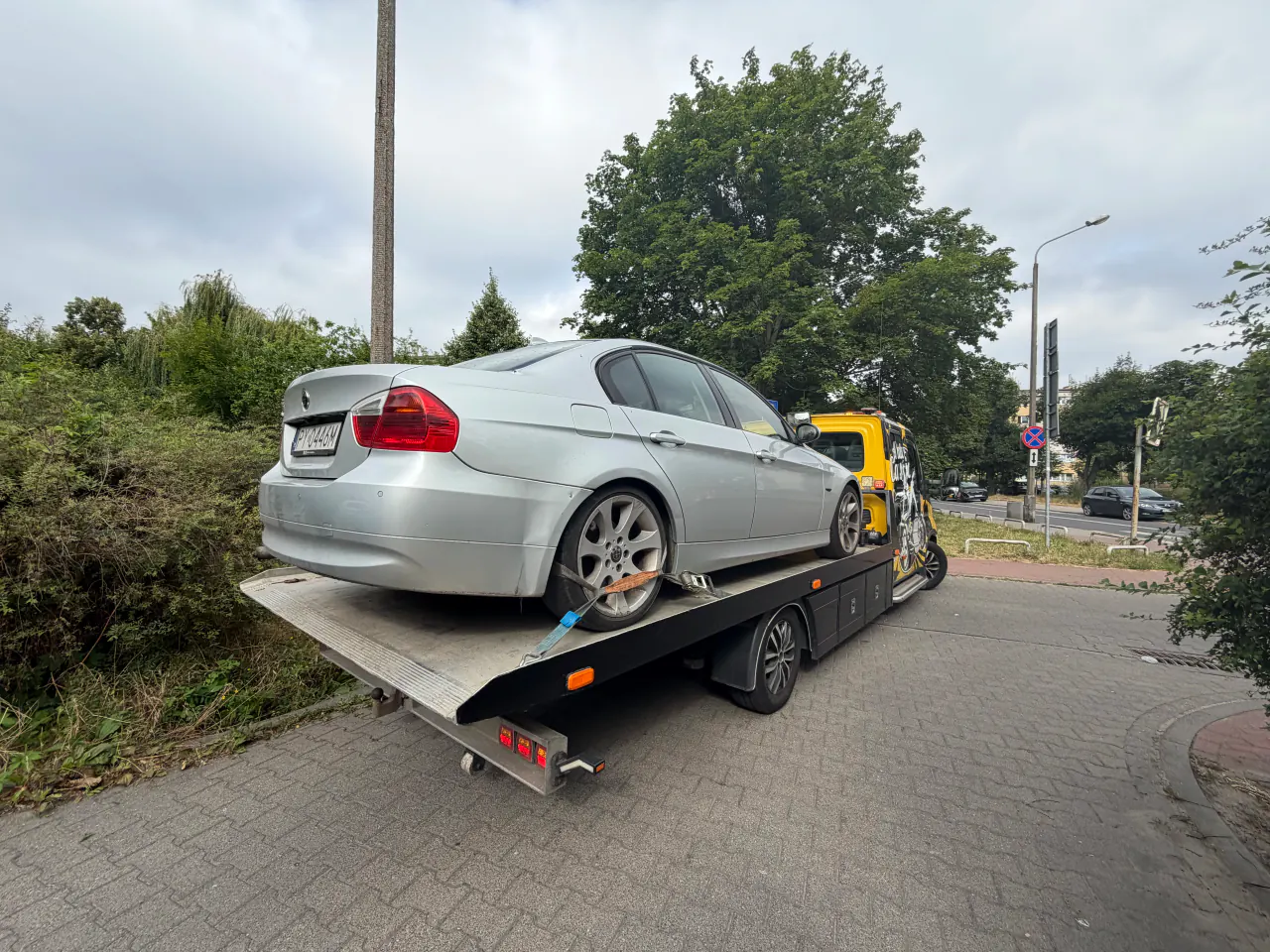 Srebrny samochód zabezpieczony pasami na platformie autolawety