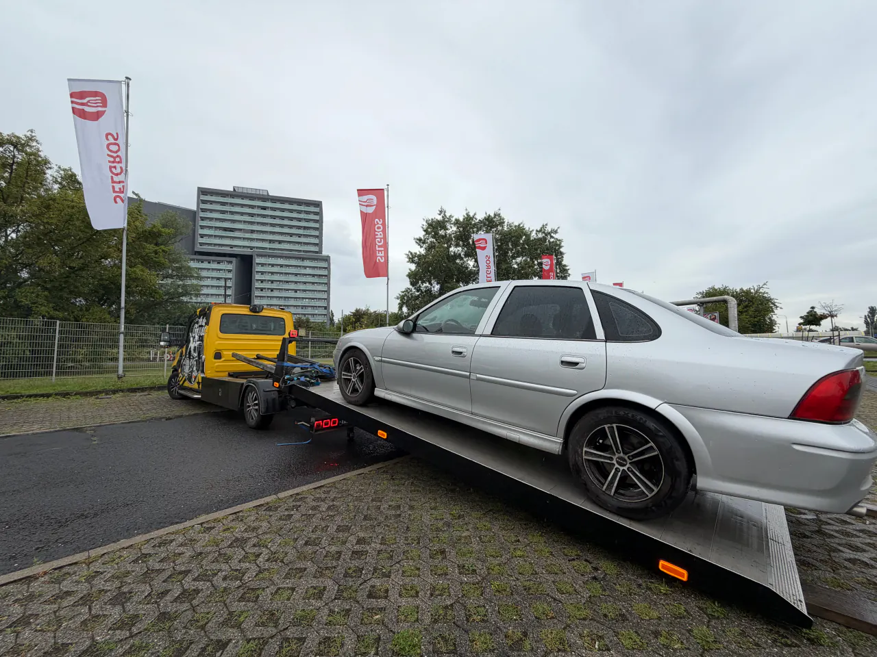 Srebrny samochód na opuszczonej hydraulicznie platformie autolawety