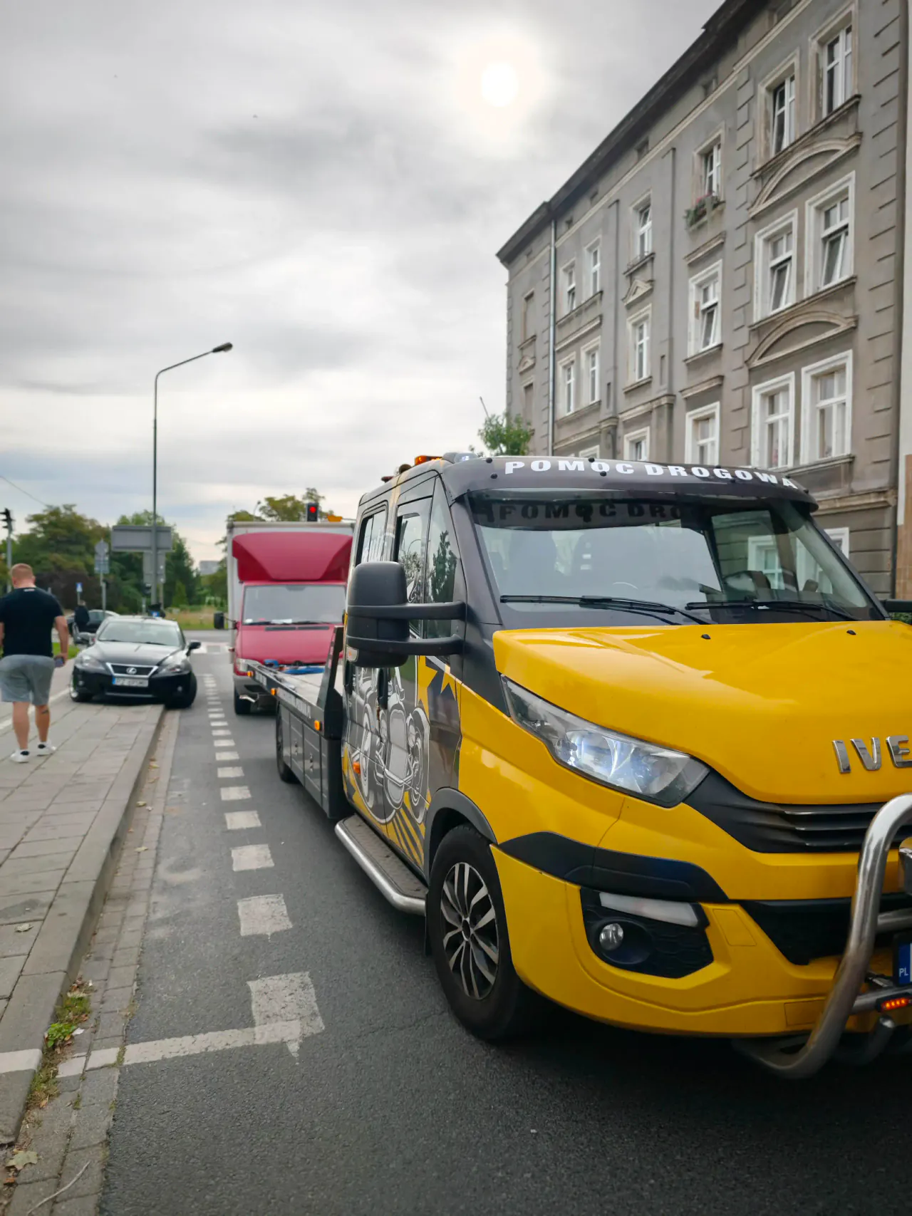 Żółta autolaweta z autem dostawczym na platformie