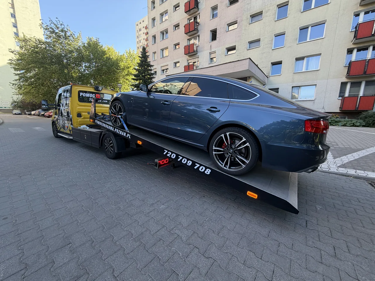Niebieski samochód przewożony autolawetą do warsztatu