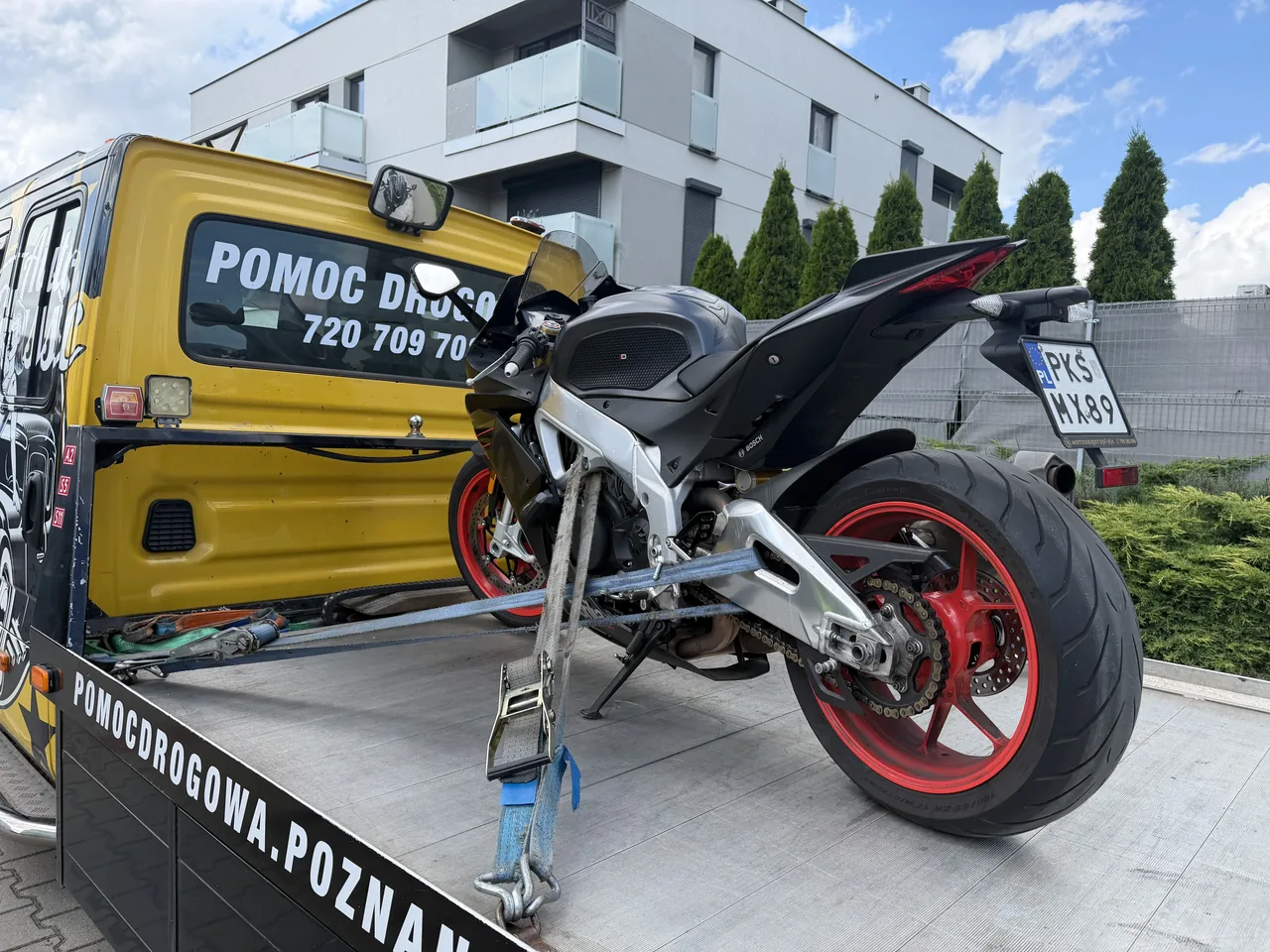 Motocykl sportowy zabezpieczony pasami na platformie autolawety